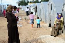 A woman st和s holding her child at a Syrian refugee camp in Turkey.